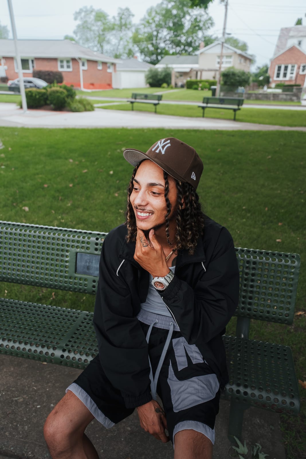 Jayggm laughing on a park bench with his hand on his chin